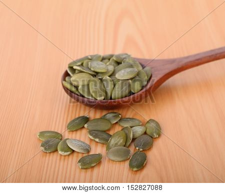 pumpkin seeds in wooden spoon on wood table