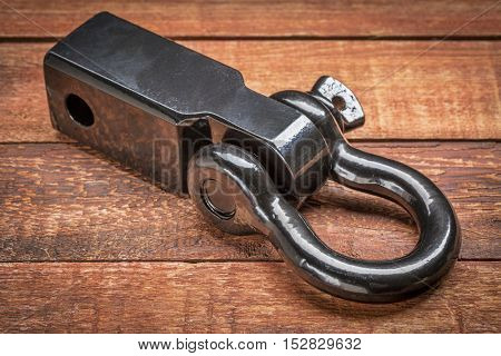 heavy duty hitch receiver with a shackle (d-ring) for vehicle recovery and towing on rustic red painted wood