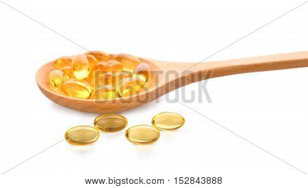 Fish oil pill in wooden spoon isolated on white