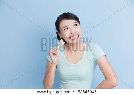 woman have sensitive teeth with ice isolatd on blue background asian