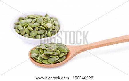 pumpkin seeds in wooden spoon and white bowl isolated on white