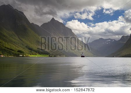 Cruiser at dramatic landscape Hjorundfjord, Fjordland, Norway