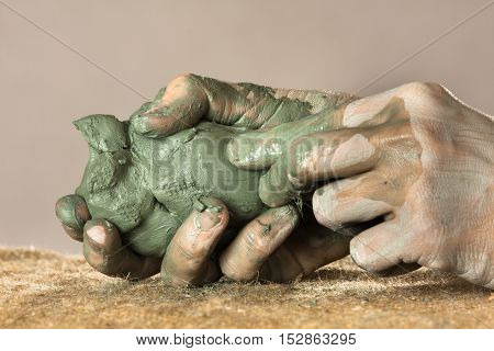 hands of ceramist moulding from blue clay