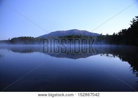 blue lake with trees on a hazy morning overlooking Mt. Katahdin