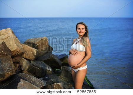 Pregnant smiling woman on the sandy beach