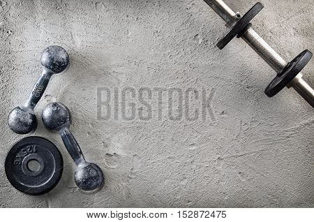 Fitness or bodybuilding concept background. Product photograph of old iron dumbbells on grey, conrete floor in the gym. Photograph taken from above, top view with lots of copy space