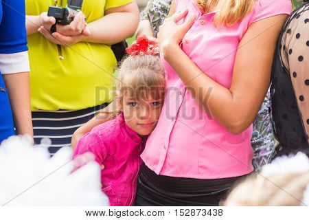 Five-year girl standing in the crowd and clung to her mother