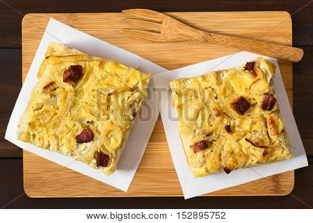 Traditional German Zwiebelkuchen savory onion cake pieces made of onion bacon and cream sauce on yeast dough photographed overhead with natural light (Selective Focus Focus on the top of the cake pieces)