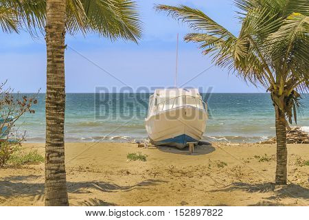 White yatch aground at empty beach in Puerto Lopez town Ecuador South America