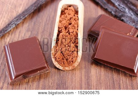 Powdery Cocoa, Dark Chocolate, Fragrant Vanilla Sticks On Wooden Surface