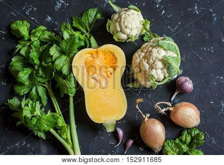 Fall vegetables on a dark background - pumpkin cauliflower celery onion garlic. Top view