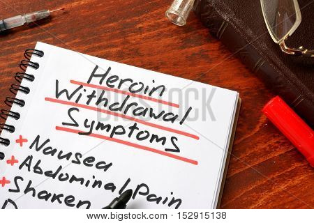Heroin withdrawal written on a note. Drugs addiction concept.