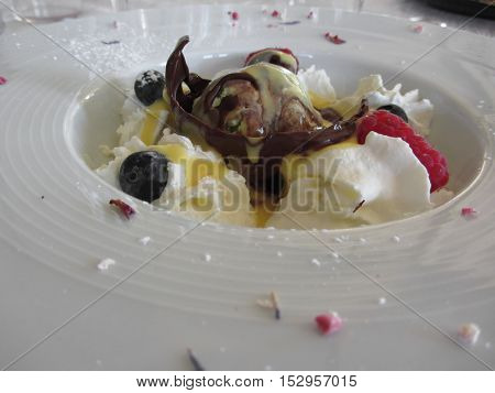 Melted chocolate ball with zabaglione cream whipped cream raspberries and blueberries