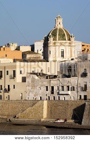 TRAPANI ITALY - AUGUST 10 2016: Waterfront of Trapani Sicily with the dome of the 15th century's Saint Lorenzo's Cathedral.