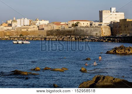 TRAPANI ITALY - AUGUST 10 2016: Waterfront of Trapani Sicily with the 15th century fortifications and the dome of the Saint Lorenzo's Cathedral.