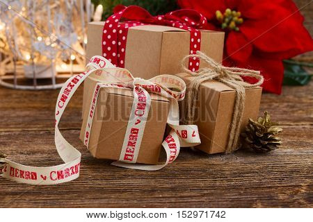 Carton handmade gift boxes on wooden background, poinsetia or christmas star flower in background