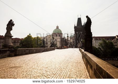 Prague, Czech Republic. Charles Bridge with its statuette, Old Town Bridge Tower, St. Francis Of Assissi Church in the background.