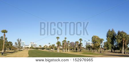 A green lawn stretching from Encanto park to downtown of Phoenix Arizona; Copy space in clear blue sky