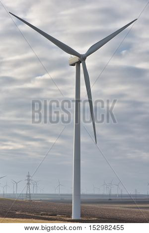 Eolian field and wind turbines farm with cloudy sky