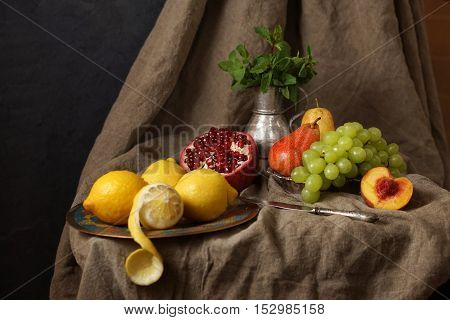 Still life in the Studio, pomegranate, grape, lemon. Beautifully laid on the rough fabric.
