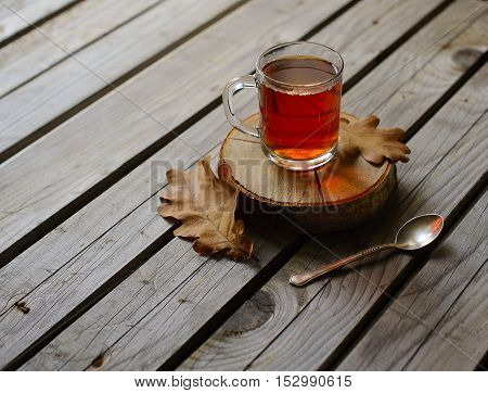 Herbal tea in glass cup on wood bacjground with leaf.