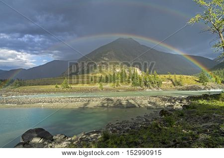 Rainbow over the river. Argut River merger with Katun. Altai Mountains Russia. August.