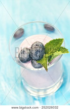 Fresh Berries Of Blueberries In Yogurt With Mint Leaves