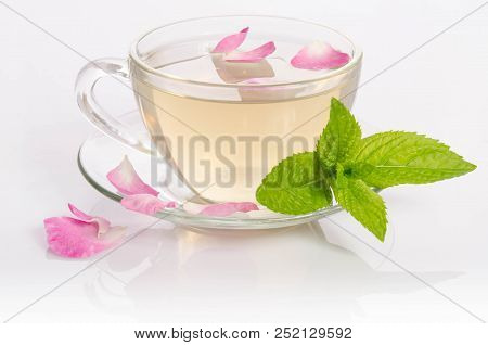 Glass Cup Of Tea With Mint Leaves And Rose Petals On Light Table