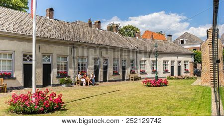 Doesburg, Netherlands - June 28, 2018: People Sitting On A Bench In Front Of Their House In Doesburg