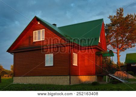 Wooden House Under Green Metal Roof Sunset Lihgts Photo