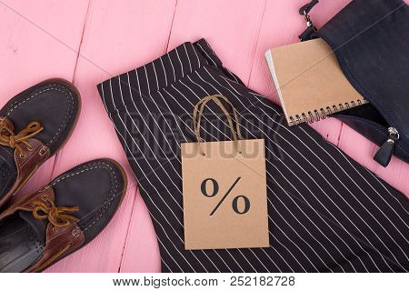 Female Fashion Stuff - Bag, Trousers, Shoes, Gift Bag With Discount Sign, Note Pad On Pink Wooden Ba