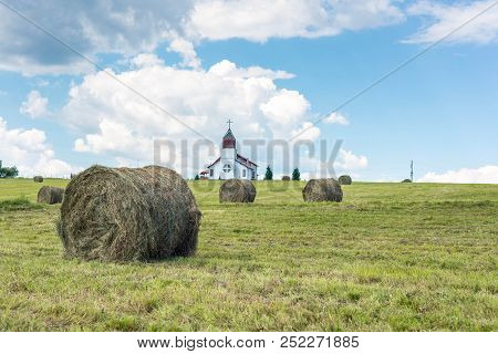 Ciba, Romania- 05 August 2018: Agricultural Landscape, Focus On The Grass Bale, Catholic Church On T