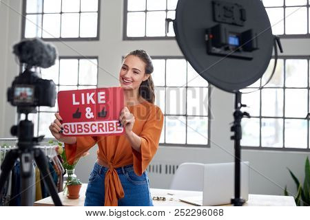 Pretty woman vlogger recording video for her channel using professional camera equipment