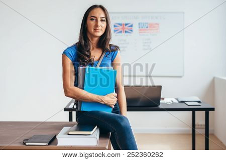 Female Student Sitting At Table Smiling And Looking At Camera