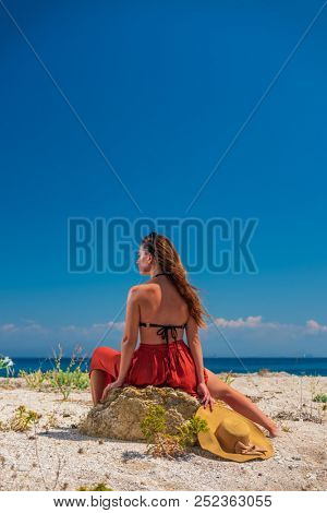 Woman in red outfit posing at the beach in Greece