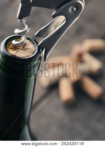 Close Uo Of A Wine Bottle With Bottle Opener On A Dark Background