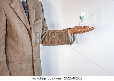 Businessman Holding An Hourglass Isolated On White Background - Time Is Money Concept.