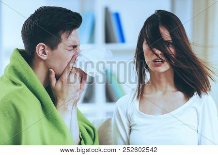 Sick Brunette Male At Cute Shocked Girl. Runny Nose And Cough. Disease Beautiful Couple. Treatment A