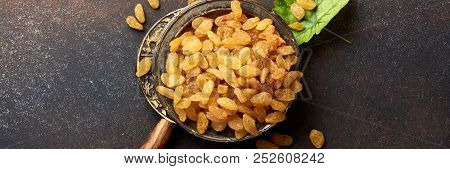 Heap Of Yellow Raisins On Brown Concrete Background. Top View Of Dried Grapes.