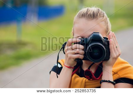 Female Photographer In The Field With Camera Taking Pictures