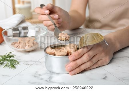 Woman With Tin Can Of Conserved Tuna At Table