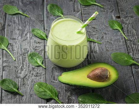 Fresh Smoothie In A Glass Glass With Avocado On A Wooden Table With Spinach Leaves. Fitness Product.