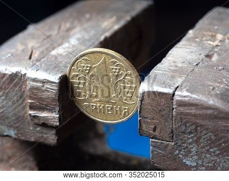 Hryvnya Coin Clamped In A Metal Vise. Currency And Ukrainian Economy Under The Onslaught, The Concep