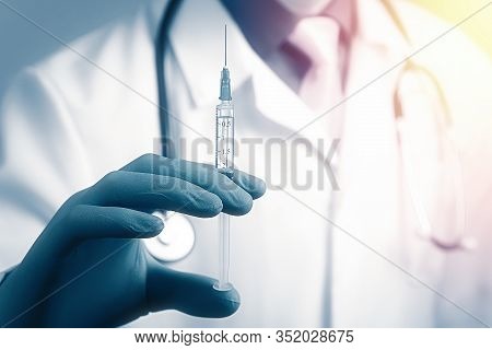 Close Up View Of Medical Syringe In Rubber Blue Glove Dressed Hand, Man Chest In White Medical Robe 