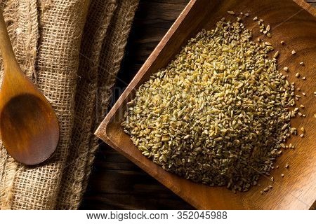 Uncooked, Raw Freekeh Or Firik, Roasted Wheat Grain, On Wooden Plate With Wood Spoon On Brown Table 