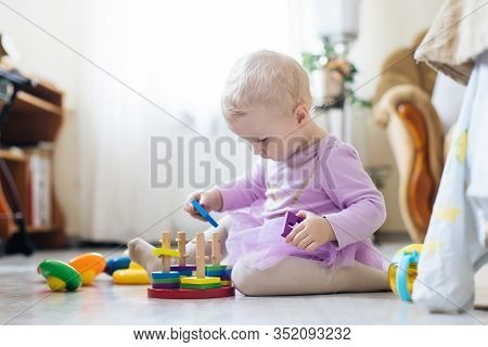Girl Plays Toys In Living Room. Montessori Wooden Toy Folded Pyramid. Circle, Quadra, Triangle, Rect