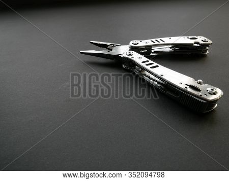 Multi Tool With Steel Handles On A Black Paper Background. Top View