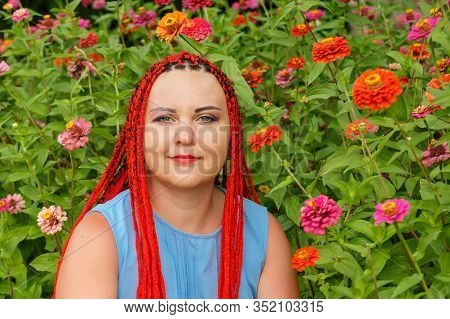 Closeup Of A Young Woman With Red Hair Among Red Orange Flowers.