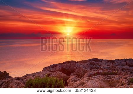 Beautiful Colorful Sunrise At The Sea With Dramatic Clouds, The Sailing Boat And Sun Shining