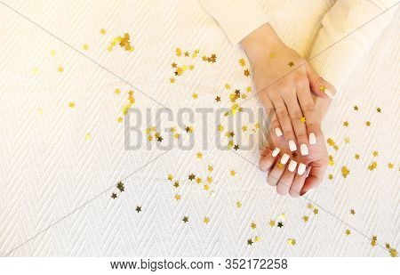Top View Of Anonymous Lady Demonstrating Manicured Hands With White Nail Polish Over Blanket With Go
